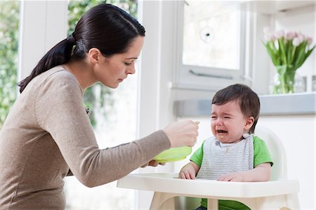 Mother feeding crying baby son Stock Photo - Premium Royalty-Free, Code: 614-05955650