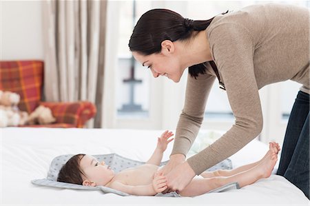 pregnant woman laying down - Young woman changing baby son Stock Photo - Premium Royalty-Free, Code: 614-05955653