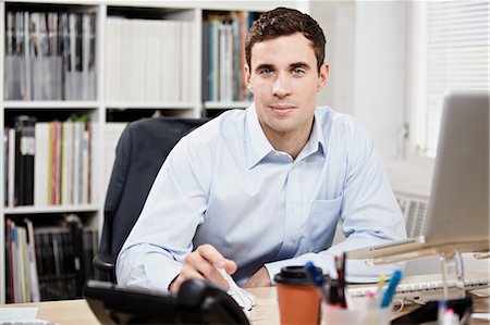 smiling brunette man looking at laptop - Office worker at his desk Stock Photo - Premium Royalty-Free, Code: 614-05955688