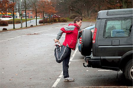 parking - Mature man stretching against car in car park Stock Photo - Premium Royalty-Free, Code: 614-06002110