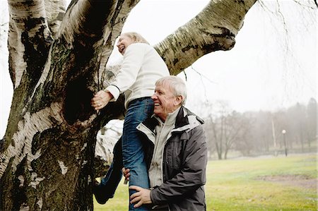 european senior park - Senior man helping woman climb tree in park Stock Photo - Premium Royalty-Free, Code: 614-06002126