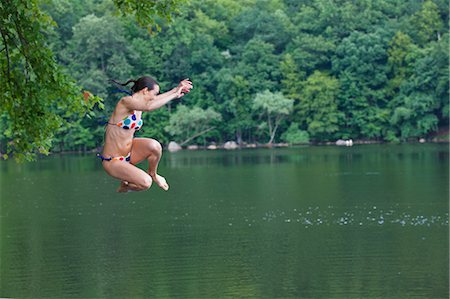 Mid adult woman leaping into river Stock Photo - Premium Royalty-Free, Code: 614-06002187