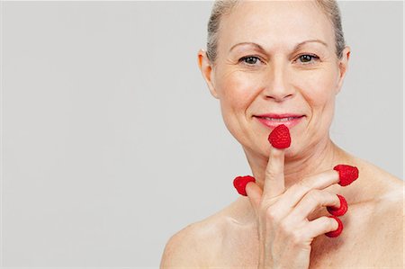 soltera (sin pareja) - Mature woman wearing raspberries on fingertips, smiling Foto de stock - Sin royalties Premium, Código: 614-06002260