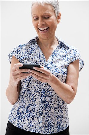 fun people on white background - Senior woman using cellphone, studio shot Stock Photo - Premium Royalty-Free, Code: 614-06002349