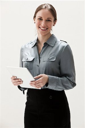 Portrait of young businesswoman smiling and using digital tablet, studio shot Stock Photo - Premium Royalty-Free, Code: 614-06002365