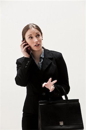 Portrait of young businesswoman using cellphone, studio shot Stock Photo - Premium Royalty-Free, Code: 614-06002360