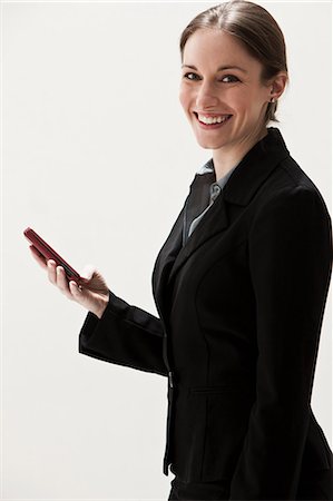 Portrait of young businesswoman using cellphone, studio shot Stock Photo - Premium Royalty-Free, Code: 614-06002362
