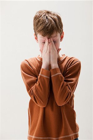 Boy in brown sweater rubbing eyes, studio shot Stock Photo - Premium Royalty-Free, Code: 614-06002395