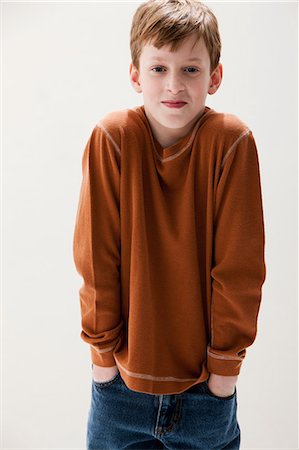 Boy in brown sweater with hands in pockets, studio shot Stock Photo - Premium Royalty-Free, Code: 614-06002392