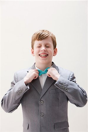 Boy wearing grey suit adjusting bow tie, studio shot Stock Photo - Premium Royalty-Free, Code: 614-06002426