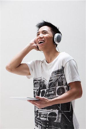 Young Asian man using digital tablet with headphones, studio shot Stock Photo - Premium Royalty-Free, Code: 614-06002447