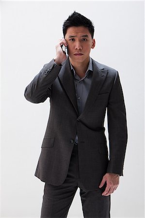 Young Asian businessman using cellphone, studio shot Foto de stock - Sin royalties Premium, Código: 614-06002452