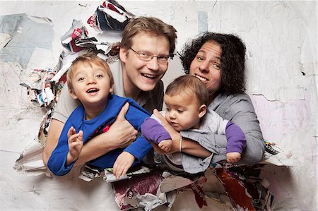 family looking at camera indoor - Happy family busting through a wall Stock Photo - Premium Royalty-Free, Code: 614-06002610