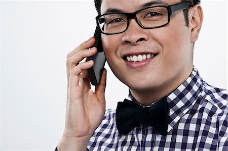 Young man using cellphone against white background Stock Photo - Premium Royalty-Free, Code: 614-06044094