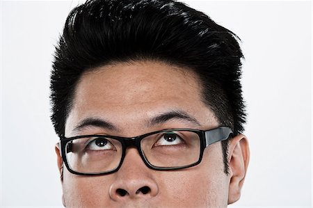 filipino ethnicity - Young man looking up against white background, close up Stock Photo - Premium Royalty-Free, Code: 614-06044095