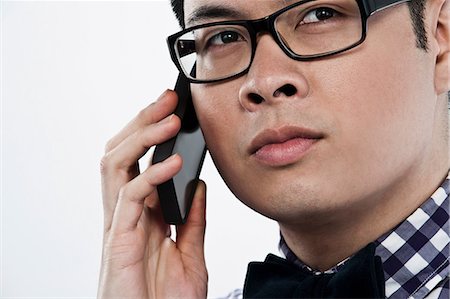 Young man using cellphone against white background Stock Photo - Premium Royalty-Free, Code: 614-06044093