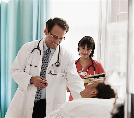 simsearch:696-03401784,k - Doctor and nurse checking on patient in hospital bed Stock Photo - Premium Royalty-Free, Code: 614-06044392