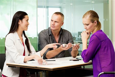 Office colleagues discussing new technologies on desk Stock Photo - Premium Royalty-Free, Code: 614-06044503