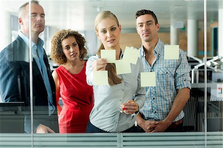 Office colleagues arranging adhesive notes on office window Foto de stock - Sin royalties Premium, Código: 614-06044576