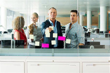 Office colleagues arranging adhesive notes on office window Foto de stock - Sin royalties Premium, Código: 614-06044578