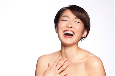 Young woman laughing against white background Stock Photo - Premium Royalty-Free, Code: 614-06044654