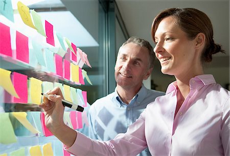 Two businesspeople writing on adhesive notes on window Foto de stock - Sin royalties Premium, Código: 614-06043655