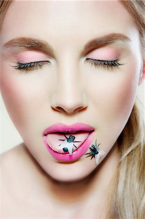 sultry face - Young woman with plastic fly on tongue Stock Photo - Premium Royalty-Free, Code: 614-06116189