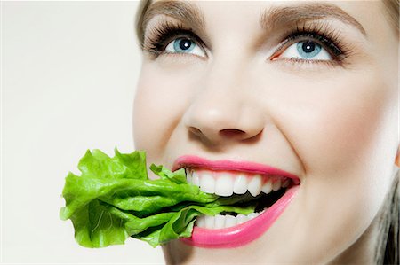 satisfaction eating - Young woman biting lettuce Stock Photo - Premium Royalty-Free, Code: 614-06116191