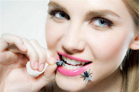 smile teeth - Young woman biting plastic fly Stock Photo - Premium Royalty-Free, Code: 614-06116201