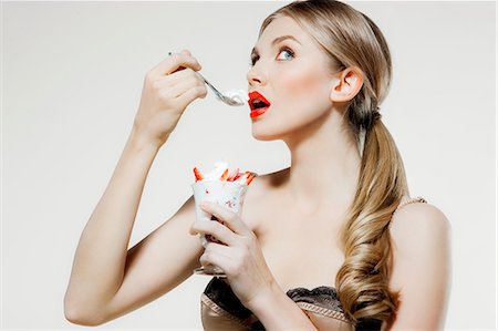 simsearch:614-06116197,k - Young woman eating strawberries and cream Stock Photo - Premium Royalty-Free, Code: 614-06116214