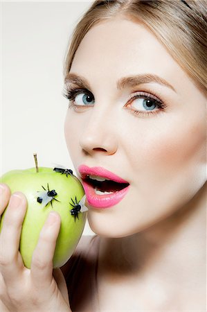 portrait of woman with fruit on head - Jeune femme eating apple avec mouches dessus Photographie de stock - Premium Libres de Droits, Code: 614-06116221