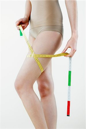 Young woman measuring thigh with tape measure Fotografie stock - Premium Royalty-Free, Codice: 614-06116238