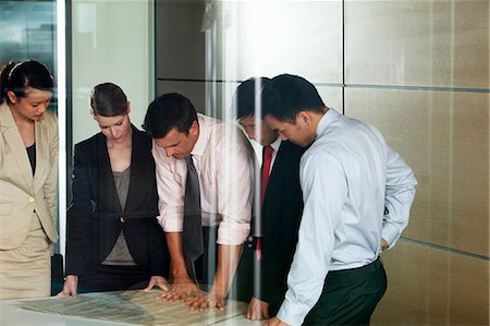 Multi racial businesspeople discussing blueprint Stock Photo - Premium Royalty-Free, Code: 614-06116530