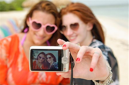 Two young women photographing themselves on digital camera Foto de stock - Sin royalties Premium, Código: 614-06168570