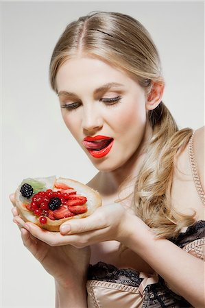 eating strawberry - Young woman eating fresh fruit tart Stock Photo - Premium Royalty-Free, Code: 614-06168646