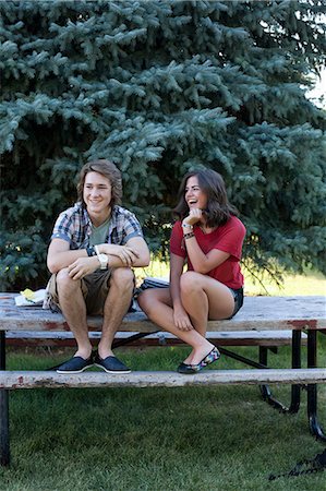 Teenage couple sitting on picnic table in park Foto de stock - Sin royalties Premium, Código: 614-06169080