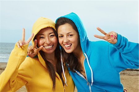 peace sign and woman - Two young women in hooded tops on beach Stock Photo - Premium Royalty-Free, Code: 614-06169370