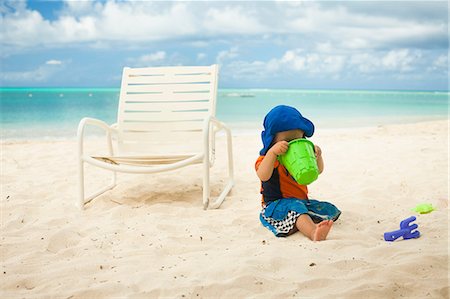 Little boy at the beach, looking into a bucket Stock Photo - Premium Royalty-Free, Code: 614-06169425