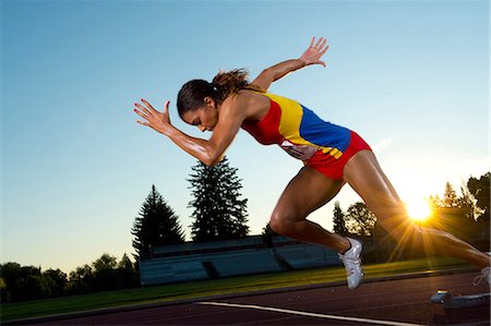 running track race - Female athlete leaving starting blocks Stock Photo - Premium Royalty-Free, Code: 614-06169462