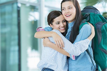 smiling women inviting - Woman embracing friend with backpack Stock Photo - Premium Royalty-Free, Code: 614-06169564