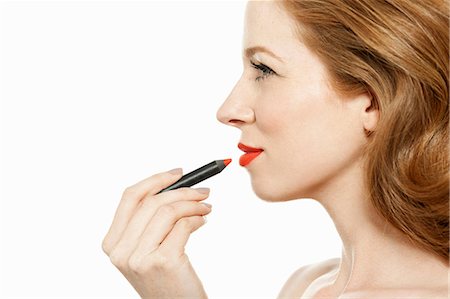 Woman applying red lipstick Stock Photo - Premium Royalty-Free, Code: 614-06311593