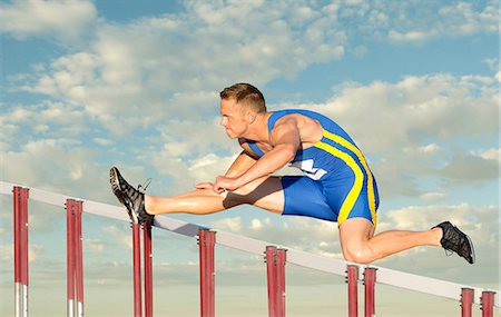 Male hurdler clearing hurdle Foto de stock - Sin royalties Premium, Código: 614-06311625