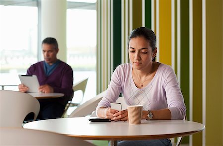 portable information device - Woman texting on smartphone, man in background using digital tablet Stock Photo - Premium Royalty-Free, Code: 614-06311698