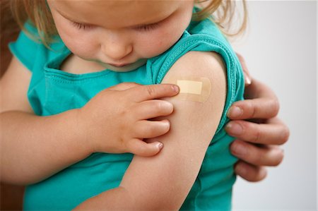 Little girl looking at plaster where she has had an injection Foto de stock - Royalty Free Premium, Número: 614-06311838