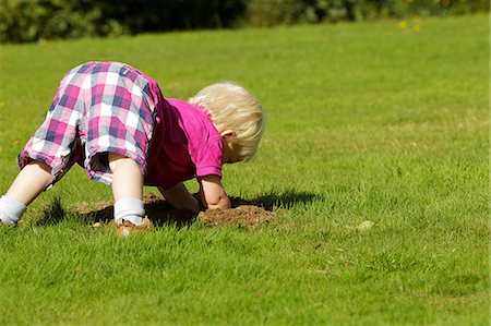 person in white polo shirt - Little boy investigating molehill Stock Photo - Premium Royalty-Free, Code: 614-06311833