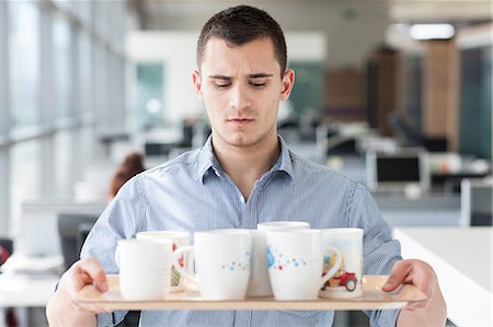 full cup - Nervous looking man carrying tray of mugs Stock Photo - Premium Royalty-Free, Code: 614-06311947