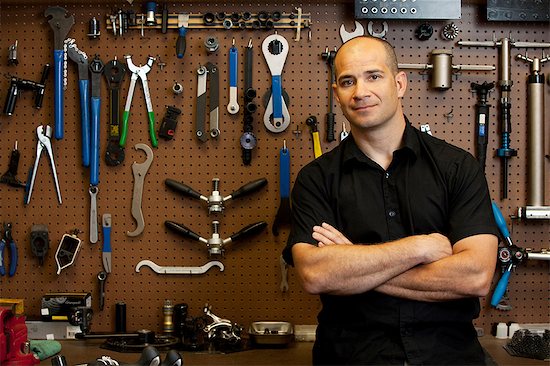 Man in front of wall of tools in workshop Stock Photo - Premium Royalty-Free, Image code: 614-06311987