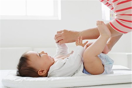 Mother changing baby girl on mat Foto de stock - Sin royalties Premium, Código: 614-06311995