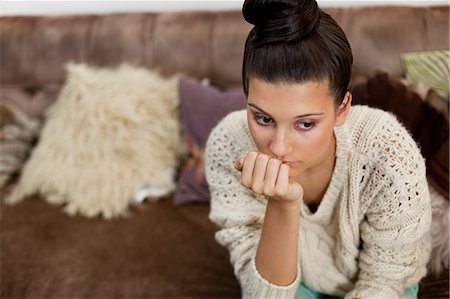 sad woman sitting alone on couch - Pensive young woman with hand on chin Stock Photo - Premium Royalty-Free, Code: 614-06335968