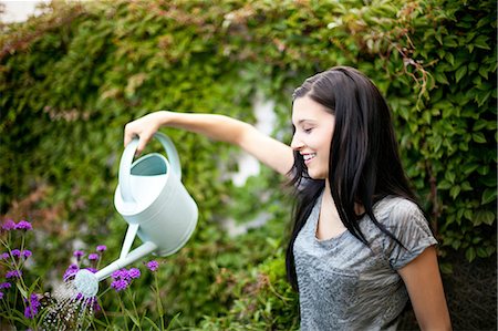 Young woman watering flowers in garden Stock Photo - Premium Royalty-Free, Code: 614-06336006